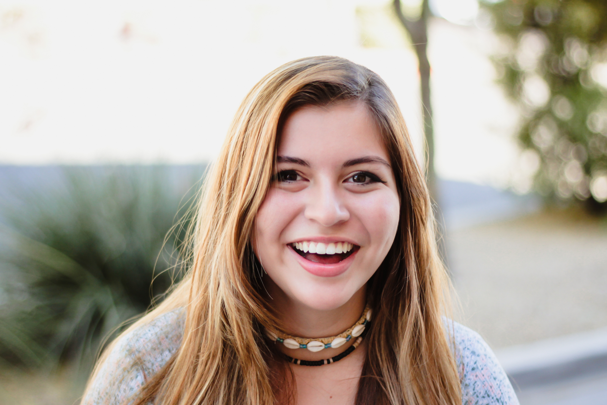 After getting orthodontic treatment for teens, a girl smiles with straight teeth showing.